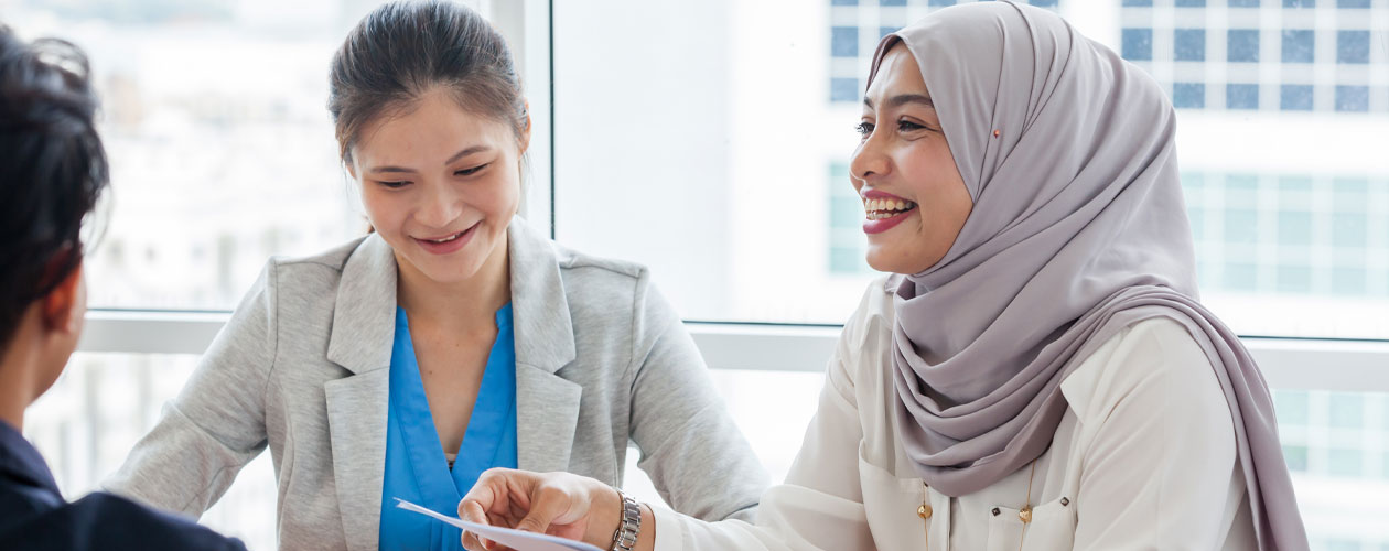 young woman wearing hijab smiling amongst others at her table