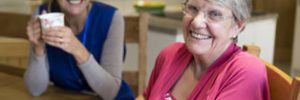 older person sitting at table with her support worker