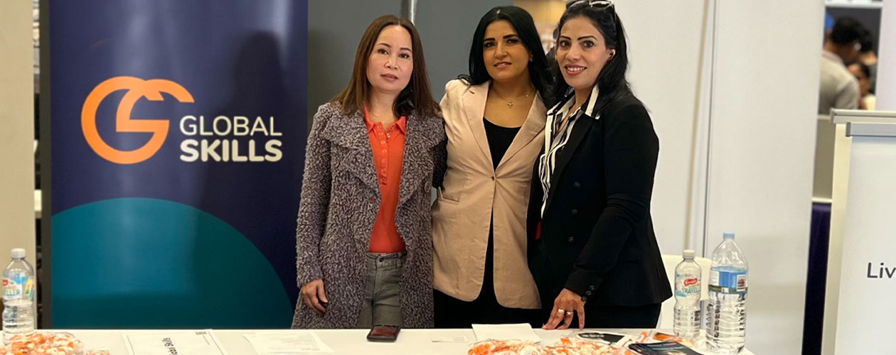 Global Skills staff standing next to the banner in our stall