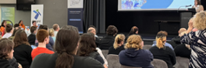 young people sitting on chairs listening to a presentation by an employer at the event