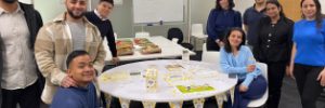 a group of Global Skills staff standing around a table with food and Biggest Morning Tea decorations