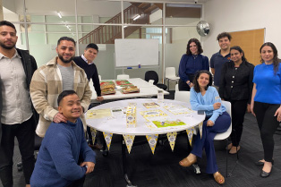 a group of Global Skills staff standing around a table with food and Biggest Morning Tea decorations