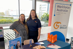 2 Global Skills staff standing behind the table at our stall.