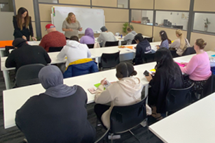 Students sitting at desk with a teacher standing at front
