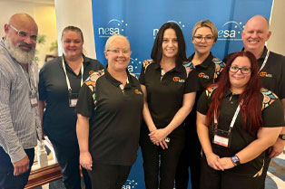 Global skills staff standing in front of NESA banner at the conference