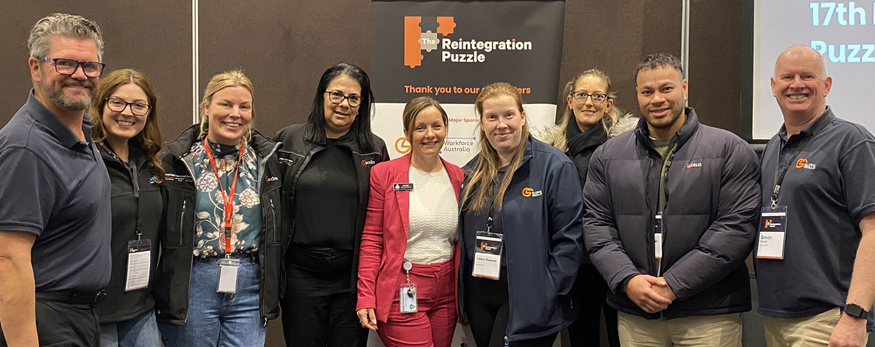 group pic of Global Skills attendees standing in front of the Puzzle Conference banner