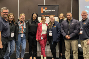 group pic of Global Skills attendees standing in front of the Puzzle Conference banner