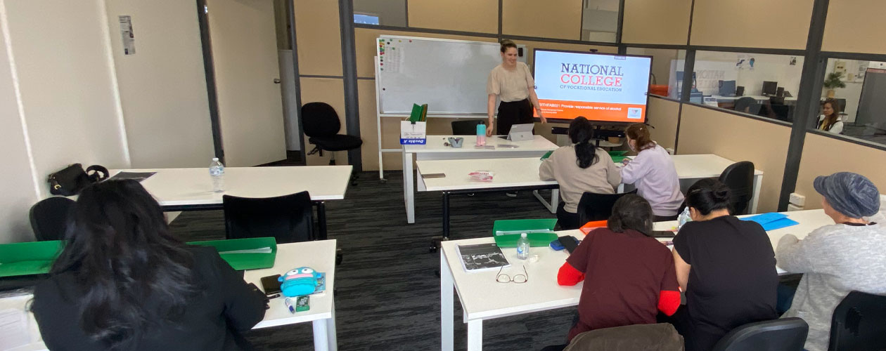Students working at desks with back to camera. Instructor facing students