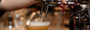 Close up view of hands using a bar tap to pour a beer