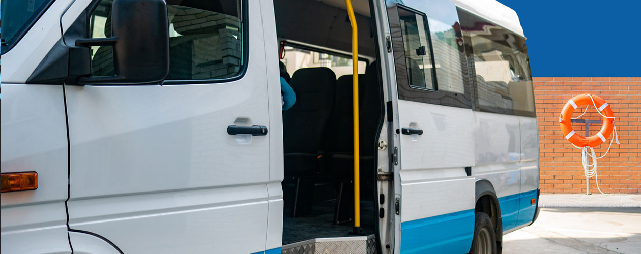 A white van with a blue stripe, parked with its door open, and a lifesaving ring visible in the background
