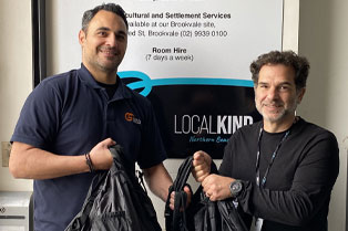 Robby and Daniel standing in front of LocalKinds banner. They are each holding some of the bags.