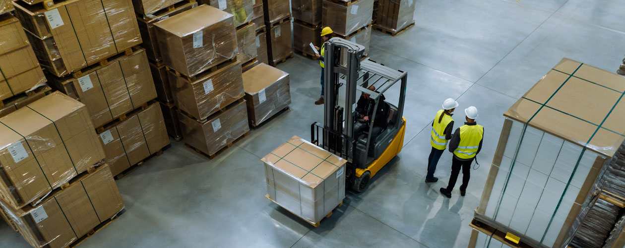op view of a warehouse featuring a forklift operator and several workers