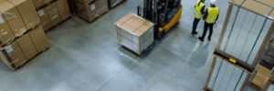 op view of a warehouse featuring a forklift operator and several workers