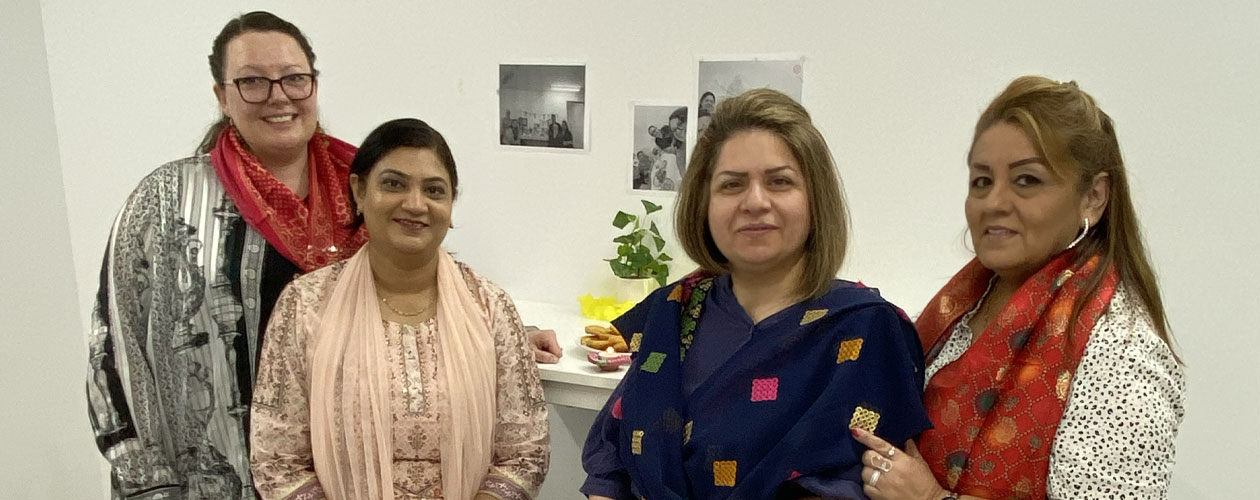 Global Skills Baulkham Hills staff standing together, wearing traditional scarves and clothing. Decorations and food are visible in the background.