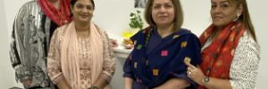 Global Skills Baulkham Hills staff standing together, wearing traditional scarves and clothing. Decorations and food are visible in the background.