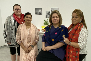 Global Skills Baulkham Hills staff standing together, wearing traditional scarves and clothing. Decorations and food are visible in the background.