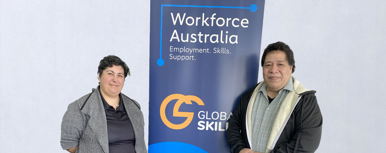 Enimoa and Vanessa standing on either side of a Global Skills banner that reads "Workforce Australia: Employment. Skills. Support." The banner includes the Global Skills logo and website.