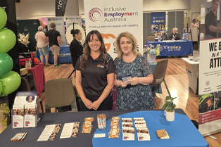 Global Skills team, Nancy and Kim, standing in front of Global Skills’ Inclusive Employment Australia banner at the Expo