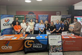 Robert from Global Skills stands with other stall holders from various community organisations behind their display tables at the event.