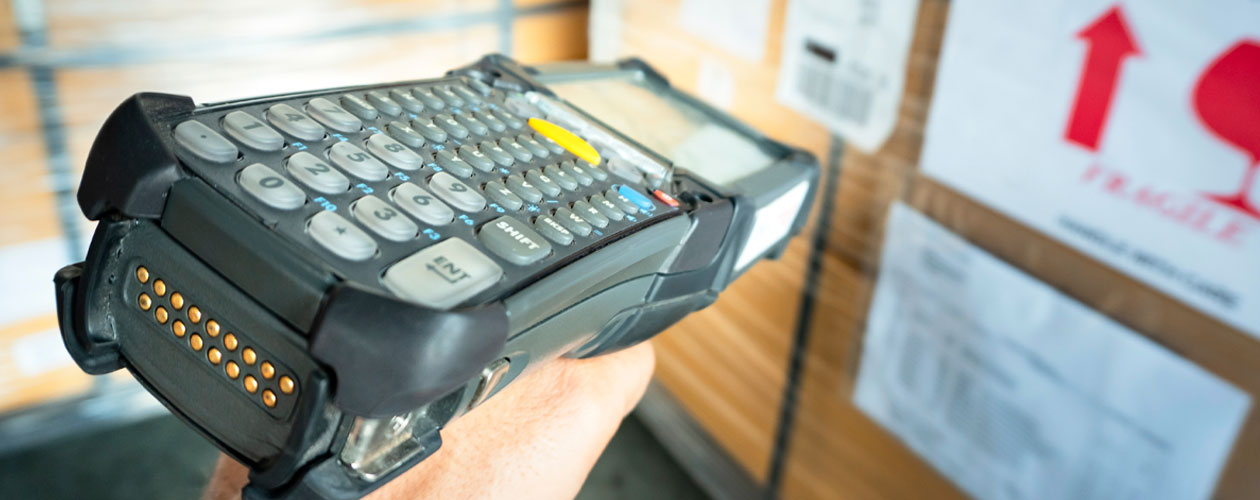 Close-up of a worker using a barcode scanner in front of stacked cardboard boxes with shipping labels. Workforce Australia and Global Skills logos appear in the bottom right corner.