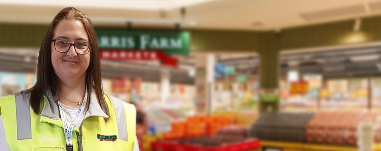 Nancie wearing a high-visibility Harris Farm Markets vest, smiling at the camera. Workforce Australia Global Skills logos appear at the bottom of the image.
