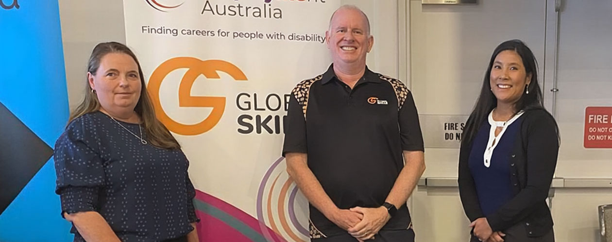 Rachael, Simon and Alyce standing in infront of Global Skills’ Inclusive Employment Australia banner.