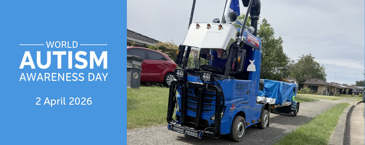 Jaycob’s blue remote-control truck is parked on a footpath, next to a road.