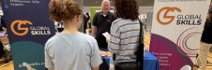 Global Skills Manager Simon speaking with attendees at our expo stall, featuring Global Skills’ Workforce Australia and Inclusive Employment Australia banners.