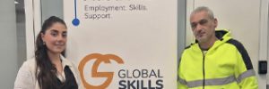 Natasha and Raad standing either side of a Global Skills Workforce Australia banner. Raad is wearing high-visibility workwear.