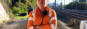 Hayley standing on railway tracks wearing high visibility clothing and a hard hat.