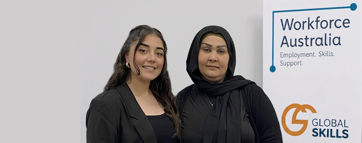 Bushra and Wasan standing in front of Global Skills’ Workforce Australia banner.
