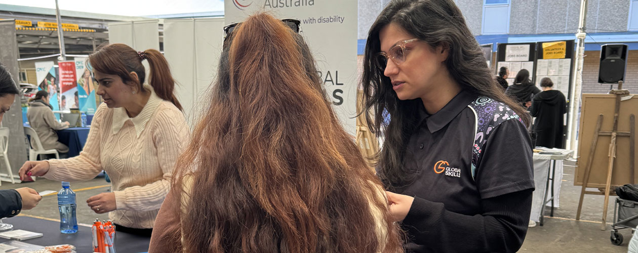 A Global Skills team member speaks with an attendee at the event. Another team member assists at our stall in the background.