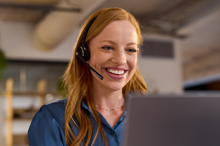 A woman wearing a black headset and blue blouse is seated at a computer in an office environment. A laptop is visible in the foreground. Workforce Australia and Global Skills logos appear in the lower right corner.