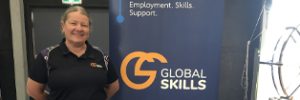 Global Skills team member, Melinda, standing beside a Workforce Australia banner at the event, with a promotional table displaying branded pens, drink bottles and other materials.