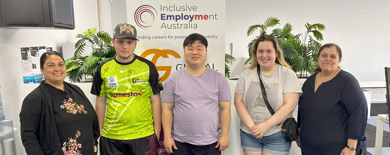 Young people and staff stand together in front of a Global Skills and Inclusive Employment Australia banner at the Mount Druitt Youth Advisory Group session.