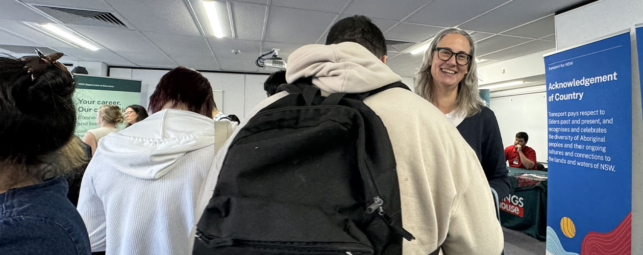 The image shows participants and Global Skills staff interacting and moving between stalls, with employers in the background.