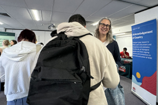 The image shows participants and Global Skills staff interacting and moving between stalls, with employers in the background.