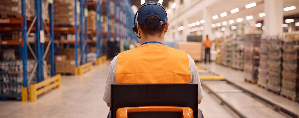A person wearing an orange high-visibility vest and headset operates a pallet mover in a warehouse. Workforce Australia and Global Skills logos appear at the bottom.