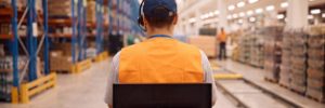 A person wearing an orange high-visibility vest and headset operates a pallet mover in a warehouse. Workforce Australia and Global Skills logos appear at the bottom.