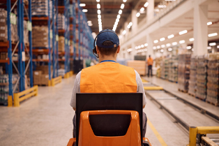 A person wearing an orange high-visibility vest and headset operates a pallet mover in a warehouse. Workforce Australia and Global Skills logos appear at the bottom.